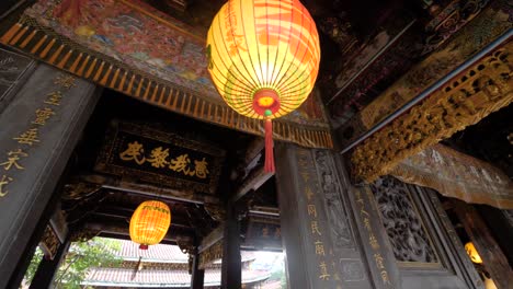 Handheld-slow-motion-shot-of-yellow-Chinese-lamp-with-symbols-hanging-in-Dalongdong-Baoan-Temple-in-Taipei,-Taiwan