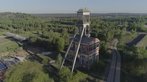 Flyby-aerial-shot-of-an-old-mine-shaft-tower-in-a-forest-background