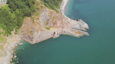 Aerial-over-head-of-Cliffside,-beside-a-beautiful-Bay