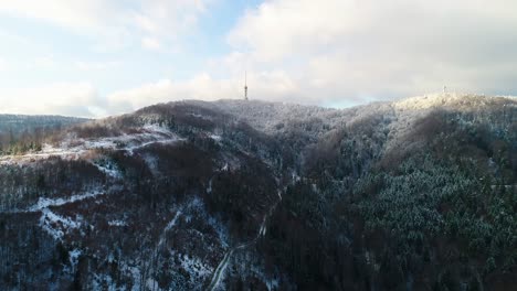 Luftaufnahme-Des-Fernsehturms-Auf-Dem-Berggipfel,-Umgeben-Von-Schneebedecktem-Wald
