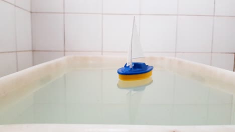 Colorful-small-plastic-boat-floats-in-a-tub