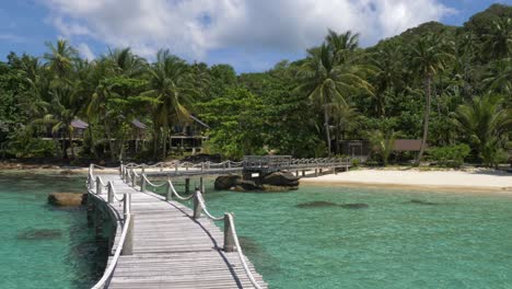 Wooden-bridge-leading-onto-a-tropical-white-sand-beach-island