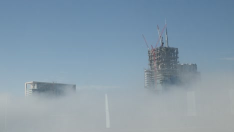 Three-skyscrapers-over-the-clouds,-one-is-under-construction