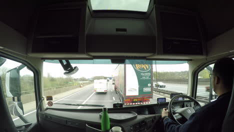 In-cab-view-of-a-HGV-driver-overtaking-a-slow-caravan-on-the-M6-motorway,-Birmingham