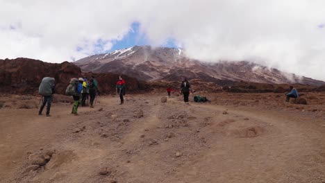 Static-shot-of-a-group-of-people-taking-a-break,-while-trekking-towards-the-summit-of-mount-Kilimanjaro,-on-a-sunny-day,-near-Horombo-hut,-in-Tanzania,-Africa