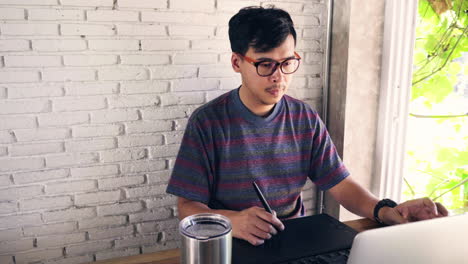 Man-graphic-designer-working-using-his-laptop,-keyboard-and-tablet