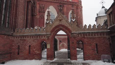 Red-brick-church-entrance-to-courtyard-dolly-in-walking-shot-in-winter-with-snow-covering-the-ground