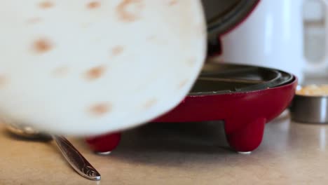 1080p-still-shot-of-tortilla-shell-being-set-onto-quesadilla-maker