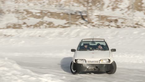 A-car-drifting-in-slow-motion-on-a-slippery-snowy-winter-race-track-road-with-tires-spinning-around-the-turn-during-a-pro-motor-sports-event-at-Isola-2000