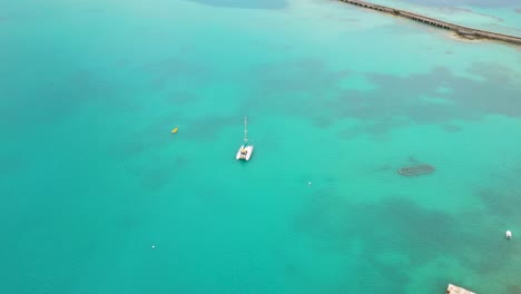 Aerial-view-of-sailboat-in-turquoise-water-by-tropical-island