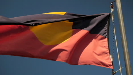 Bandera-Aborigen-Australiana-Que-Fluye-En-La-Brisa-Bajo-Un-Cielo-Azul-Claro