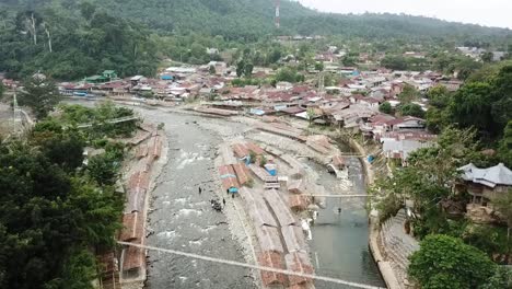 Drone-flight-over-the-river-and-village-of-Bukit-Lawan,-Sumatra,-Indonesia