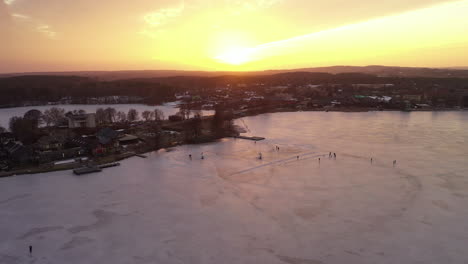 Luftaufnahme:-Flug-Sehr-Hoch-über-Dem-Zugefrorenen-See,-Während-Die-Sonne-Orangefarbenes-Licht-Auf-Das-Eis-Wirft