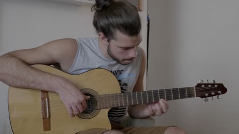 Male-sitting-at-home-playing-acoustic-guitar