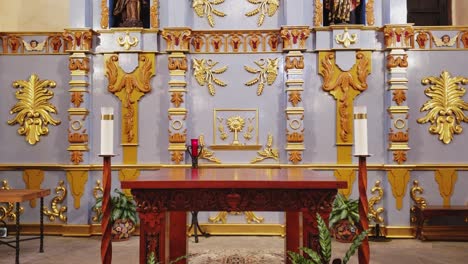 view-of-a-mission-alter-with-candels-ether-side-and-gold-religious-decor-on-the-walls
