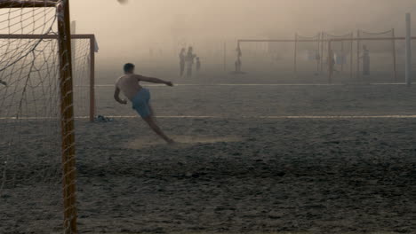 Young-male-kicking-football-mid-air-with-scissor-kick-while-dense-sea-fog-covers-the-field