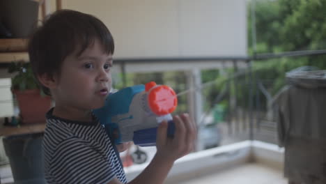 Aufnahmen-Eines-Kleinen-Kaukasischen-Jungen,-Der-Mit-Einem-Wasserpistolenspielzeug-Spielt