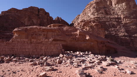 Eine-Zerbrochene-Steinmauer-In-Der-Nähe-Des-Felsigen-Hügels-Im-Wadi-Rum-Mit-Bergen-Im-Hintergrund