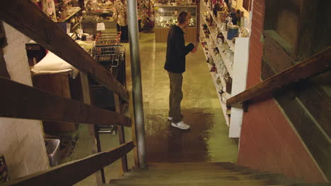 Man-Walking-Down-Stairs-at-Flea-Market-and-Looking-at-Candle