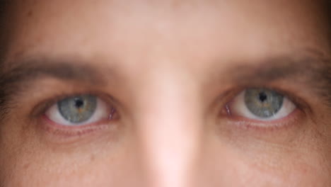 Slow-motion,-close-up-of-a-young-man-open-his-light-blue-eyes,-staring-at-the-camera-without-blinking