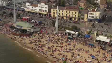 Southend-Shakedown-at-southend-seafront,-busy-crowded-beach-on-a-sunny-day-drone-footage-panning-right