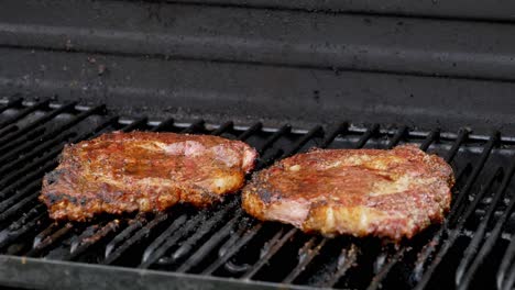 Two-juicy-rib-eye-steaks-sitting-on-the-grill-and-cooking
