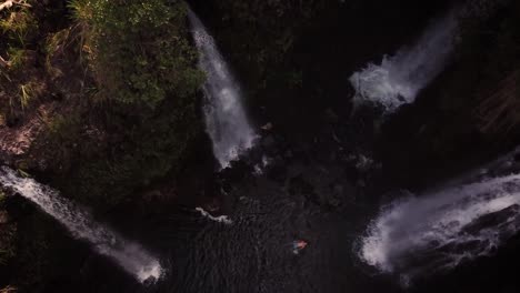 Bird's-Eye-View-of-a-man-relaxing-in-a-big-pool-of-water-with-four-huge-waterfalls-gushing-all-around-him