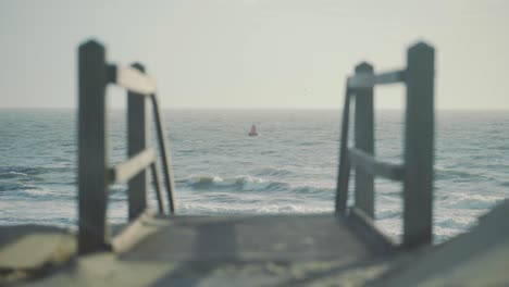 Red-buoy-float-floating-in-rough-sea-with-staircase-down-to-the-beach