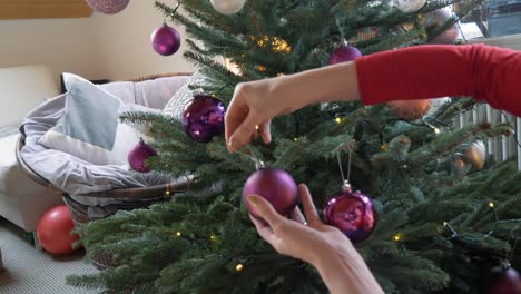 Blondes-Mädchen-Schmückt-Weihnachtsbaum-Mit-Lila-Kugeln