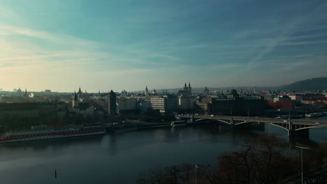 drone-flight-over-prague-vlatava-river-showing-bridges-castle-park-and-buildings-winter-sunshine