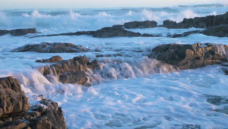 Waves-pushing-flowing-seawater-over-rocks-into-another-pool,-close-up