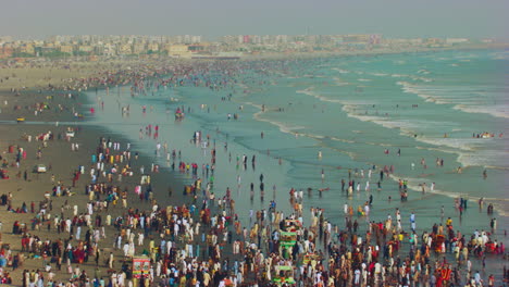 Beach-waves-and-drone-moving-together-at-Sea-View-beach-with-beautiful-blue-sea-with-long-perspective-view-of-beach-and-city,-Huge-crowd-came-to-enjoy