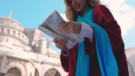 Slow-Motion:Attractive-beautiful-girl-looks-at-map-of-Istanbul-with-view-of-Sultan-Ahmet-Mosque-in-Istanbul,Turkey