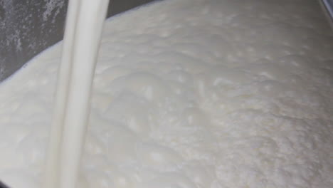 A-close-up-view-of-Milk-filling-in-a-container-by-pipe,-Making-froth-at-the-top,-A-little-messy-container-by-milk-and-a-bit-dirty-pipe