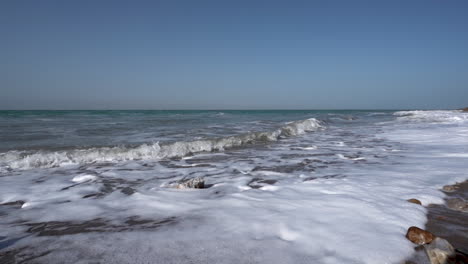Eine-Tote-Meeresküste-An-Einem-Klaren,-Sonnigen-Tag-Mit-Meeresschaum,-Der-Sich-An-Einer-Küste-Bildet