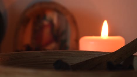 Entspannende-Hintergrunddetailaufnahme-Eines-Kräuterteeladens-Mit-Kerzen-Mit-Flackernden-Flammen,-Kräutern-Und-Einer-Holzschale