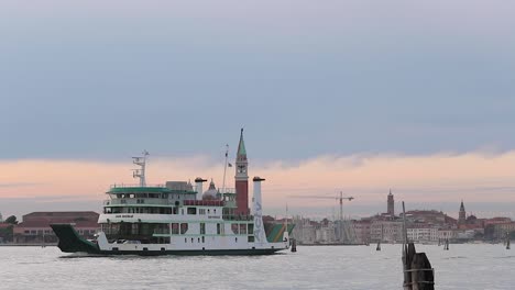 Ferry-passing-by-church-of-San-Giorgio-Maggiore-in-Venice,-Italy-at-sunset-on-cloudy-day