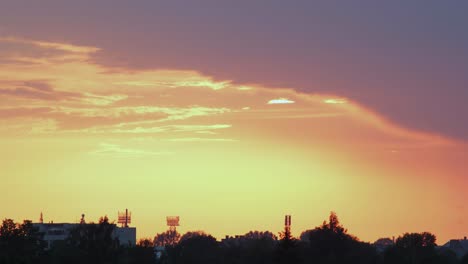 Zeitraffer-Eines-Wunderschönen-Malerischen-Roten-Sonnenuntergangs-über-Der-Stadt,-Wobei-Die-Sonne-Durch-Die-Wolken-Scheint,-Weitwinkelaufnahme