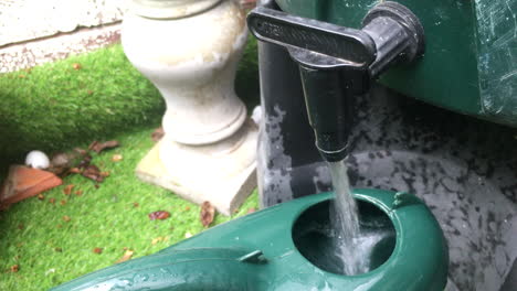 Close-up-of-a-watering-can-being-filled-up-from-a-water-butt-tap