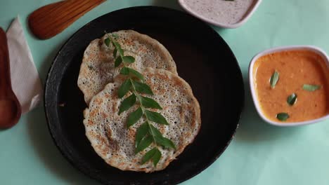 Rotating-Oothappam---Dosa---South-Indian-breakfast-using-rice-lentil-and-vegetables-served-with-coconut-chutneyisolated-on-green-background