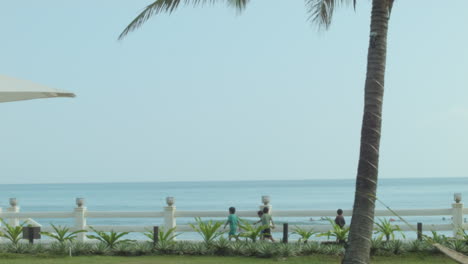 Statische-Aufnahme-Eines-Strandes-Mit-Spazierenden-Einheimischen-Kindern-Und-Surfern-Im-Hintergrund