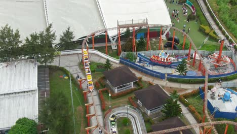 Top-down-view-tracking-the-roller-coaster-ride-moving-with-people-on-it-from-Theme-Park-in-Sky-Ranch-Tagaytay-City,-Philippines