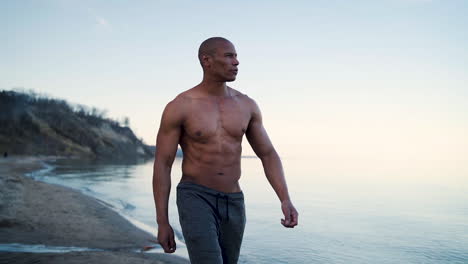 Attractive-and-muscular-man-walking-along-the-shore-in-slow-motion