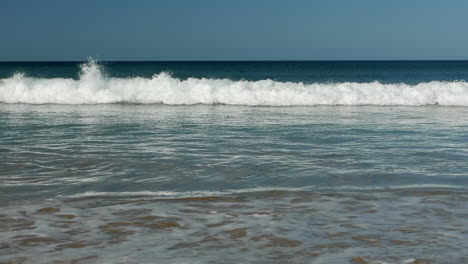 Small-rolling-waves-break-into-the-sandy-coastline