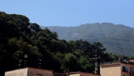 Blick-Auf-Die-Dächer-Von-Gebäuden-Mit-Bäumen-Und-Grünen-Hügeln-Im-Hintergrund