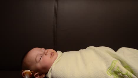 Tracking-shot-of-six-months-old-baby-sleeping-wraped-in-blanket