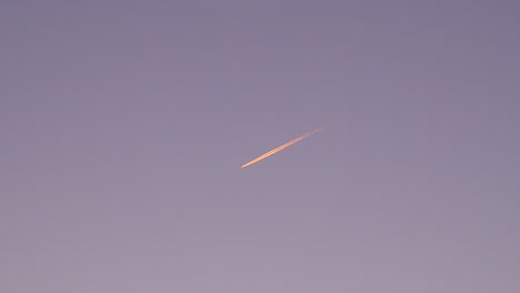Calm-Footage-of-a-Airplane-Flying-Through-Sky-at-Sunrise-And-Leaving-trails-behind