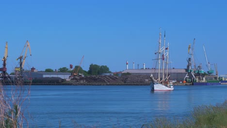 Sailing-vessel-Zawisza-Czarny-leaves-Port-Of-Liepaja-in-hot-sunny-summer-day,-medium-shot-from-a-distance