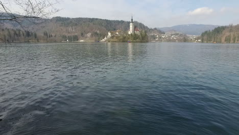 Flying-over-Bled-lake-and-view-the-island-with-small-church-located-in-the-middle-of-the-Lake-Bled,-Slovenia