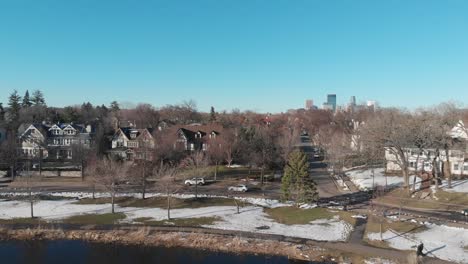 Aerial-footage-following-a-car-at-Lake-of-the-isles,nice-neighborhood-during-a-sunny-afternoon-and-showing-downtown-Minneapolis-in-the-background